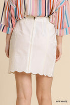 Person wearing a striped shirt and off-white skirt on a beige background