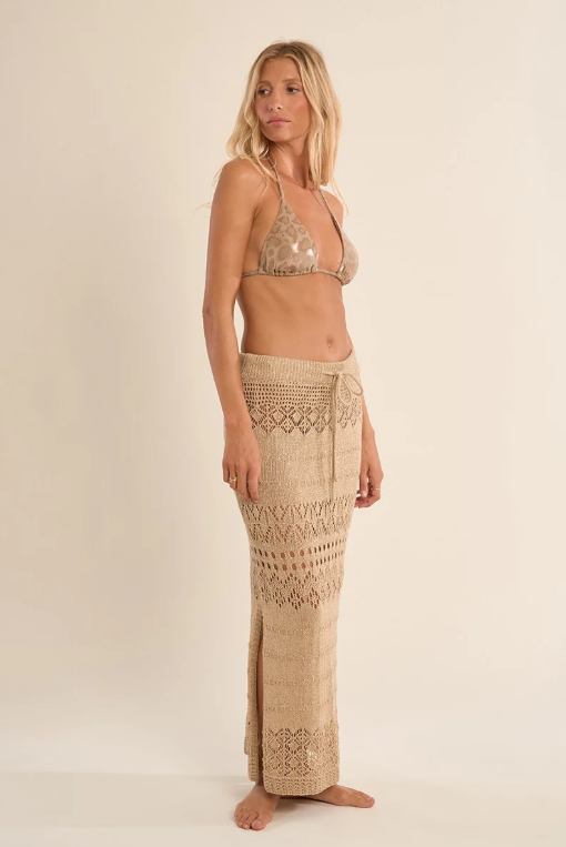 A woman wearing a gold patterned sarong and top on a plain background