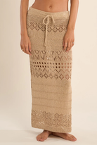 Gold crochet skirt worn by a person on a beige background