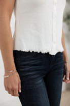 Person wearing a white blouse and dark jeans with a blurred background