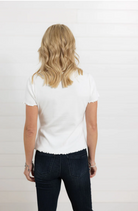 Person wearing a white t-shirt and dark jeans on a plain background