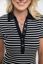 Person wearing a black and white striped polo shirt with a plain background