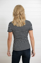 Person wearing a black and white striped shirt and dark jeans on a plain background