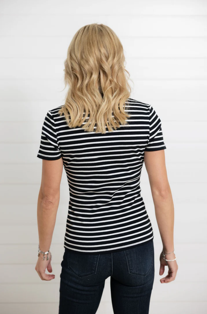 Person wearing a black and white striped shirt and dark jeans on a plain background
