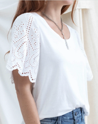 White blouse with lace details on sleeves worn by a person, with a neutral background