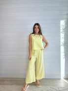 Woman wearing a yellow outfit standing against a white wall.