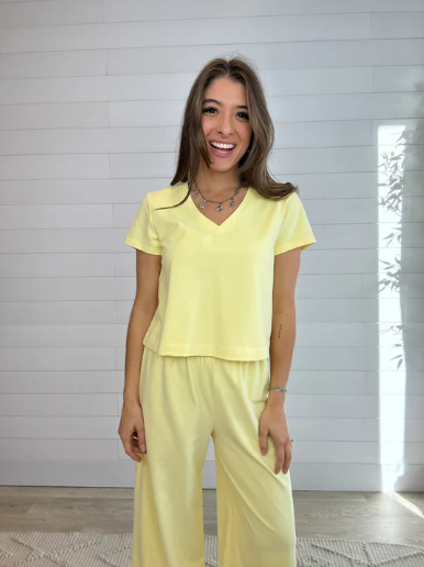 Woman wearing a yellow outfit standing in a room with white walls and wooden floor.