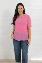 Woman wearing a pink top and blue jeans against a white background