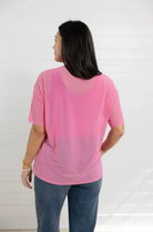 Woman wearing a pink top with a sheer overlay on a white background