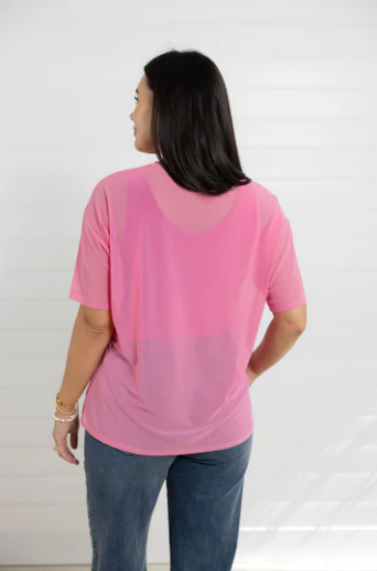 Woman wearing a pink top with a sheer overlay on a white background