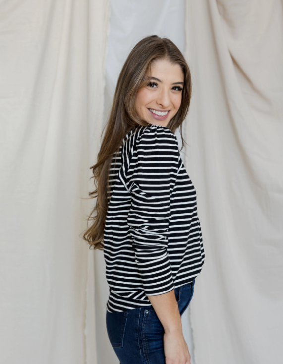 Woman wearing a black and white striped shirt against a plain background
