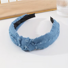 Blue denim headband with black inner accents on a white surface