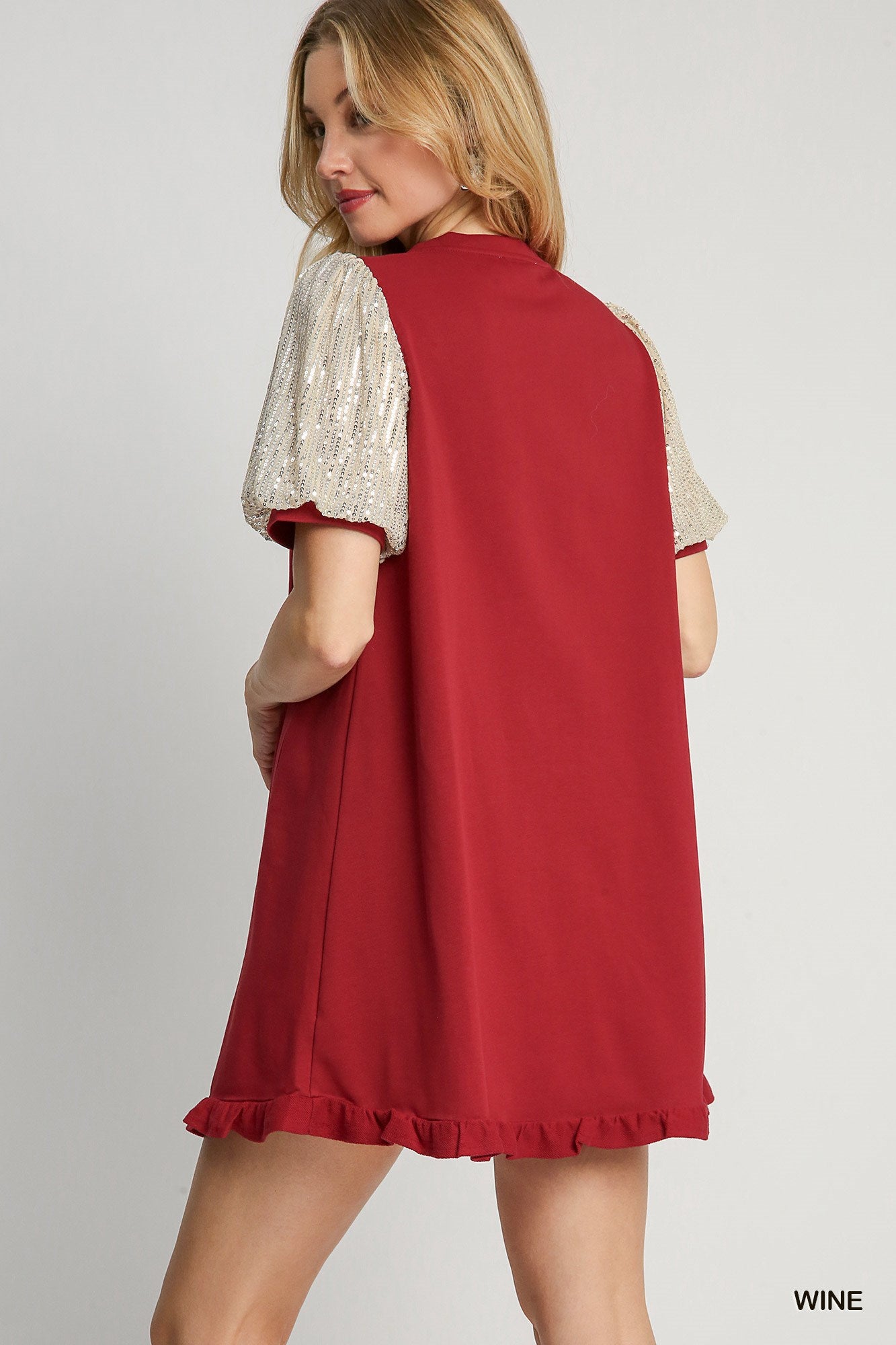Woman wearing a red dress with white lace sleeves on a gray background