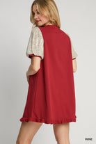 Woman wearing a red dress with white lace sleeves on a gray background