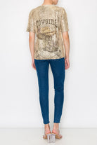 Person wearing a gold sequin 'COWGIRL' top and blue jeans on a white background