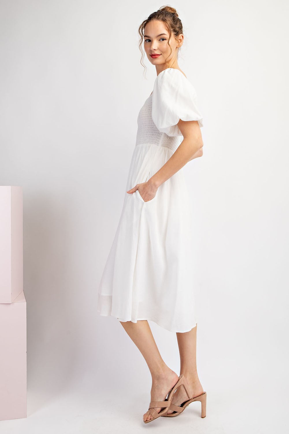 Woman wearing a white dress with puffed sleeves on a plain background