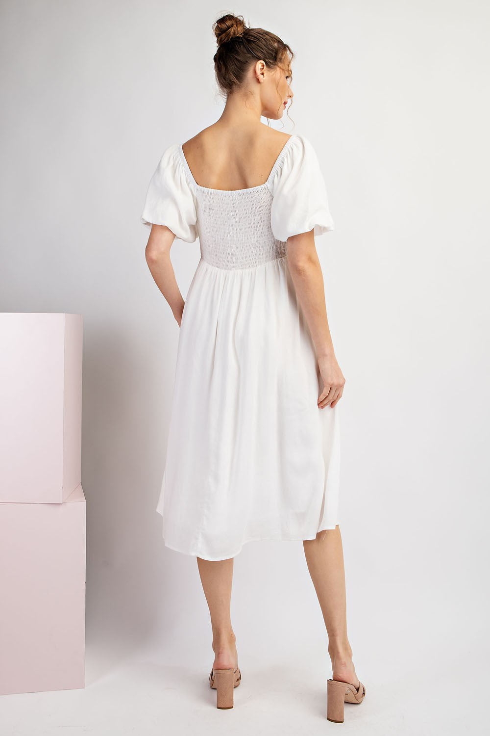 Woman wearing a white dress with a plain background