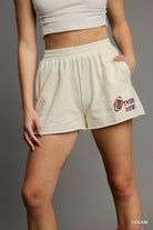 Beige shorts with colorful text and graphics on a gray background
