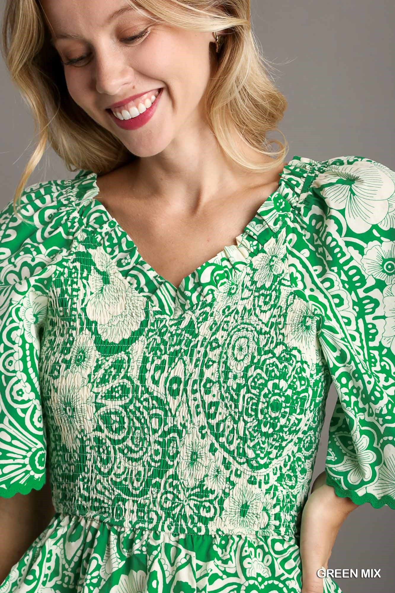 Woman wearing a green and white patterned dress against a gray background