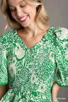Woman wearing a green and white patterned dress against a gray background