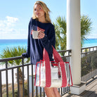 Woman holding a mug and a clear bag with a gingham pattern on a balcony with ocean view