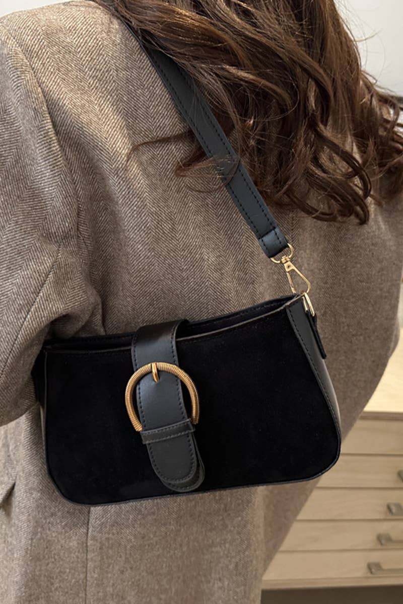 Person wearing a black handbag with a gold buckle over a gray coat.