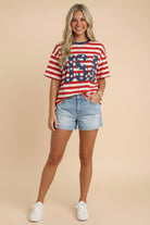 Woman wearing a red, white, and blue striped shirt with 'USA' print and denim shorts on a beige background