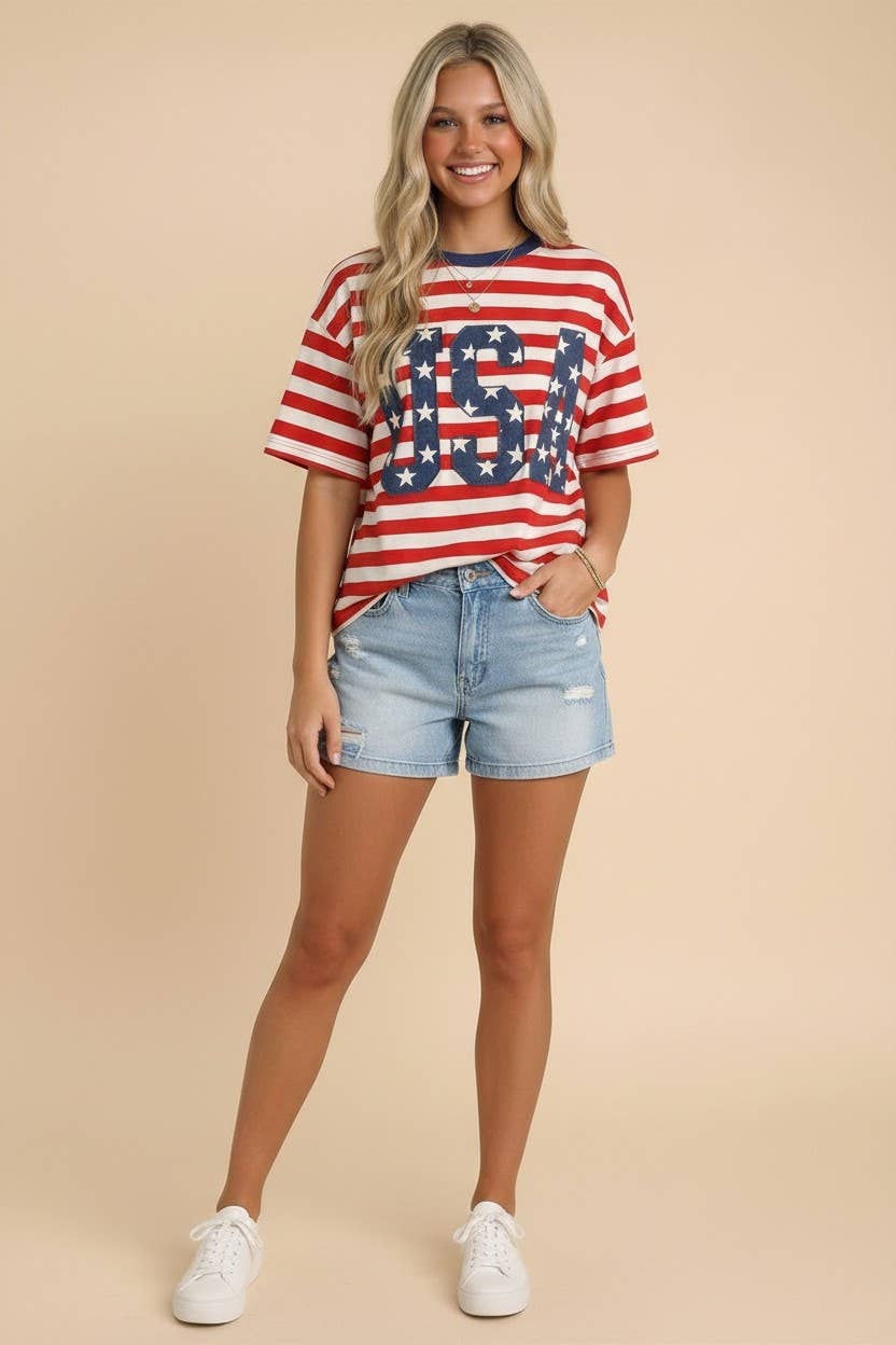 Woman wearing a red, white, and blue striped shirt with 'USA' print and denim shorts on a beige background