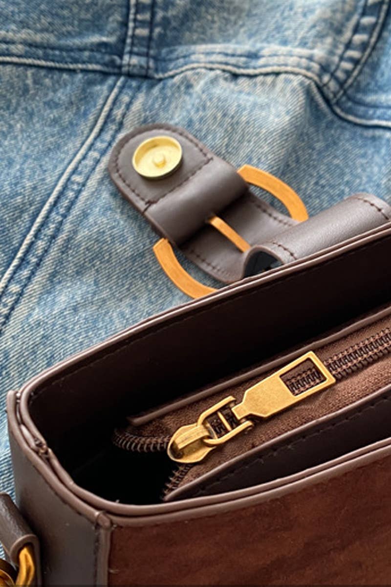 Brown leather wallet with gold zipper pull on a blue denim background