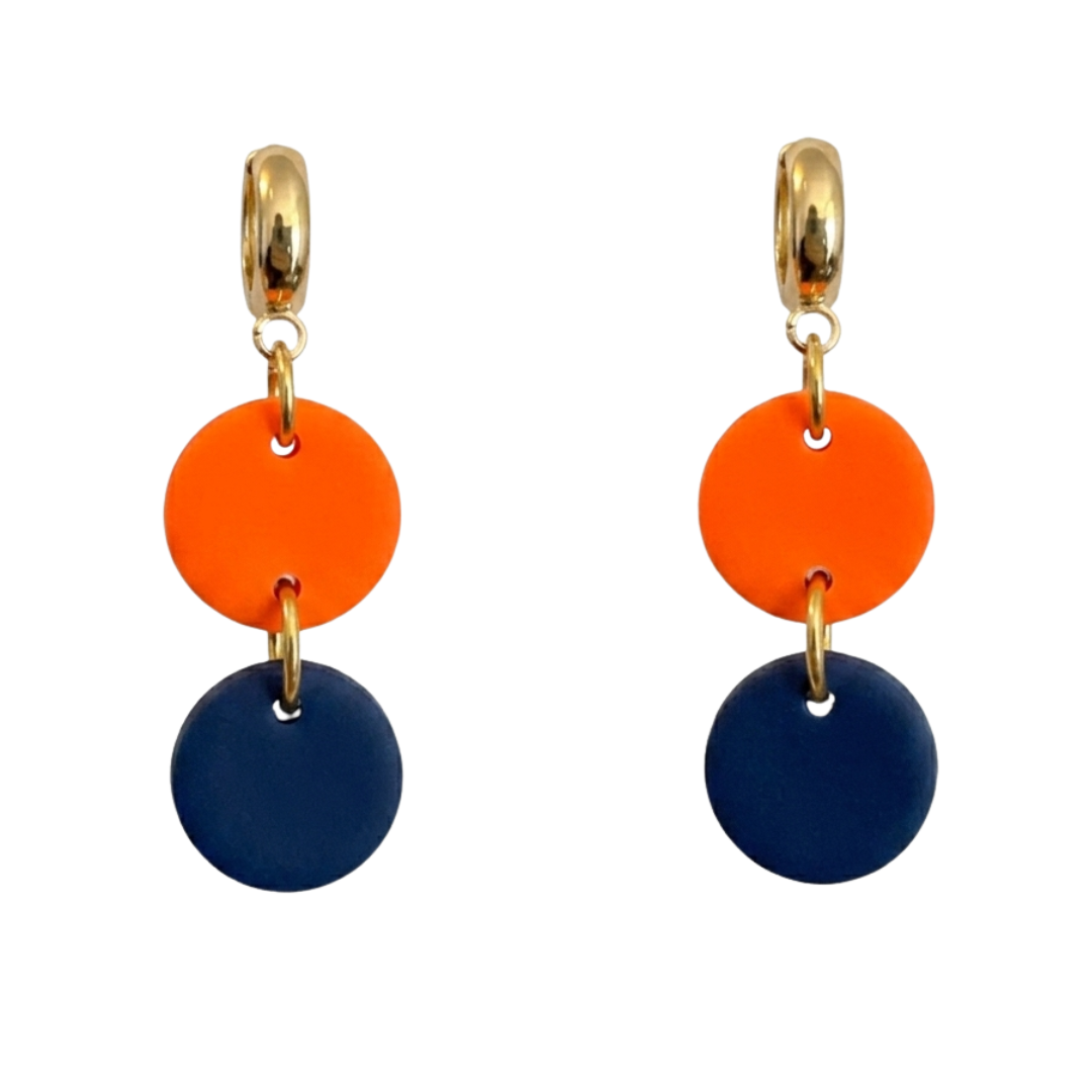 A pair of drop earrings featuring a gold-tone huggie hoop, a bright orange disc, and a matte navy blue disc, shown on a plain white background.
