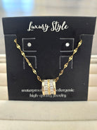 A gold chain necklace with a rectangular pavé-set stone pendant, displayed on a black card labeled 'Luxury Style'.