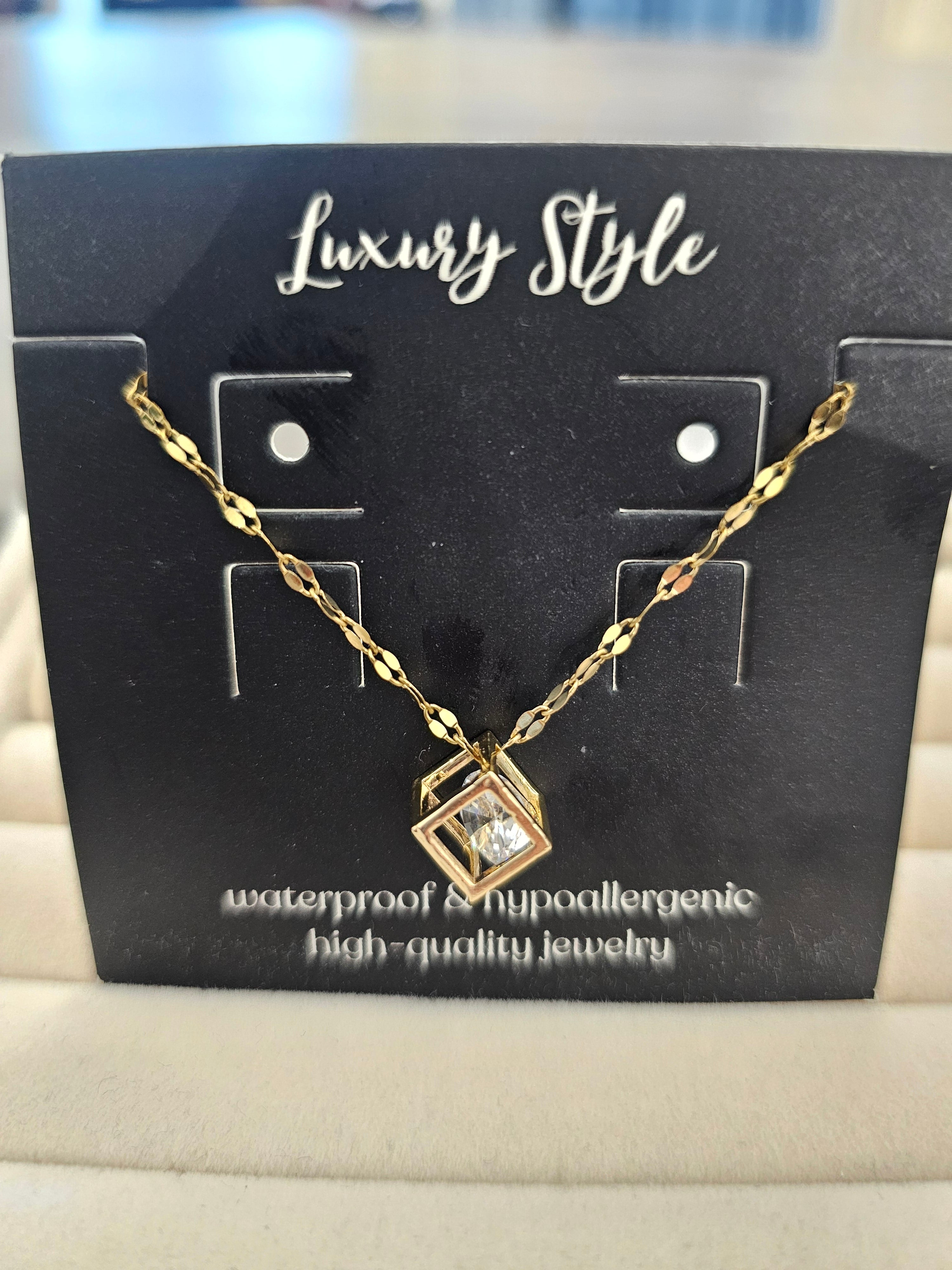 A gold chain necklace with a geometric pendant displayed on a black card labeled 'Luxury Style'.