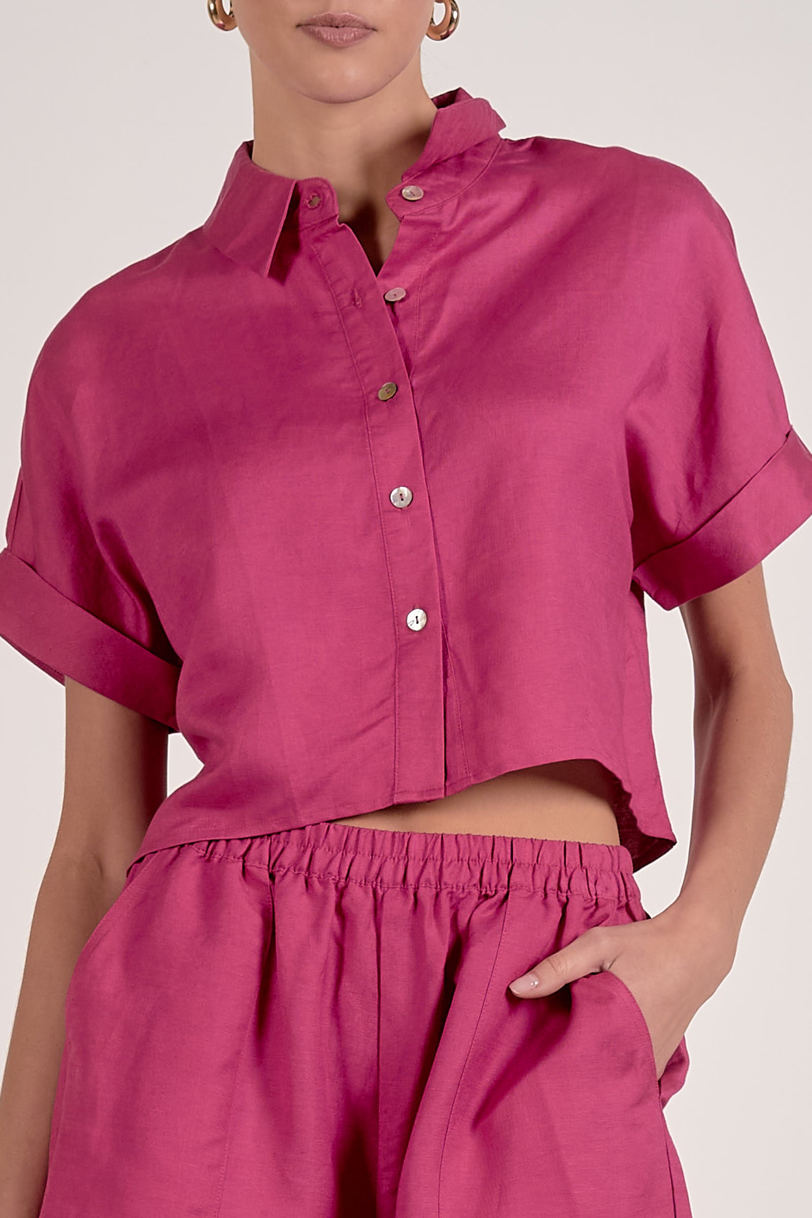 Person wearing a bright pink shirt and pants on a plain background